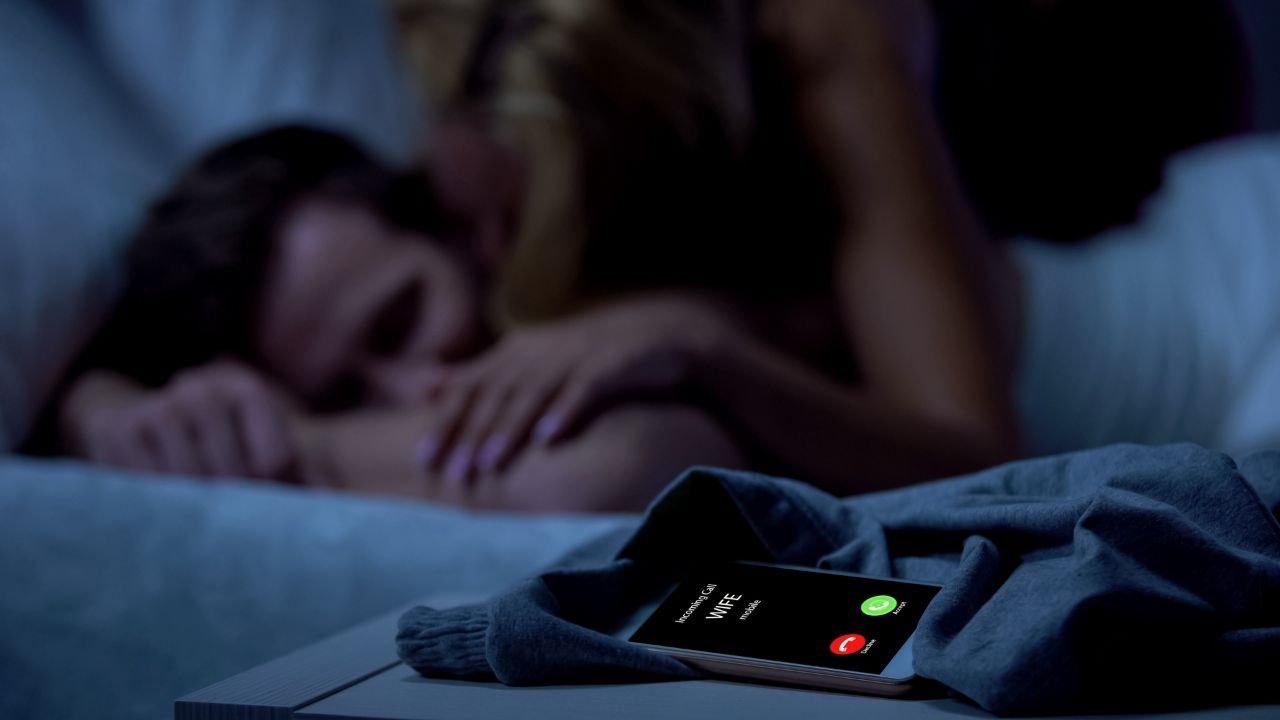 cheating husband in bed with another woman while wife rings on phone